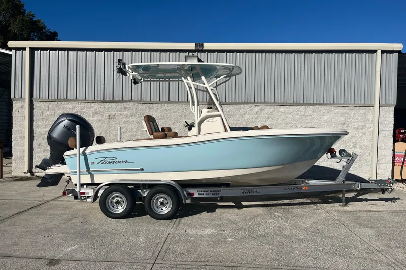 Slide: The Image of 2026 Pioneer 202 Sportfish boat on trailer, parked outside a metal building. - 14