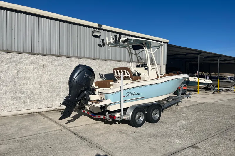 Slide: The Image of 2026 Pioneer 202 Sportfish boat on trailer, parked outdoors near a metal building. - 3