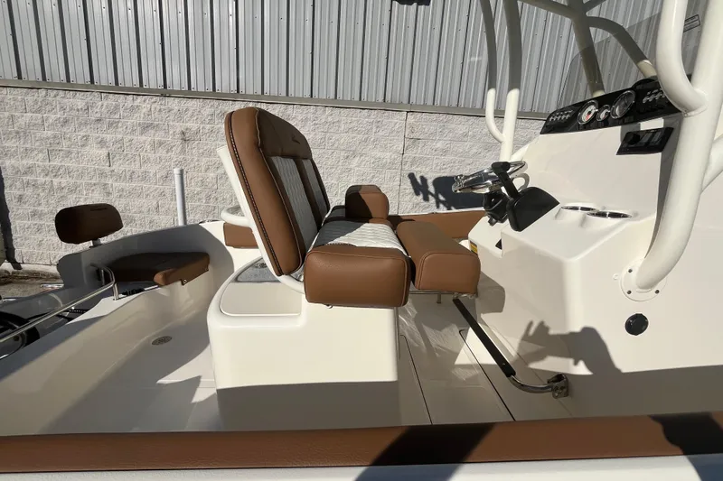 Slide: The Image of 2026 Pioneer 202 Sportfish boat interior with brown and white seating, steering console, and cup holders. - 7