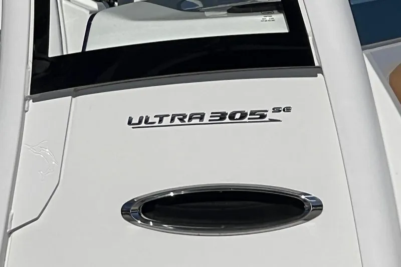 Slide: The Image of 2023 Sea Hunt Ultra 305 SE boat docked with twin engines, clear blue sky. - 6