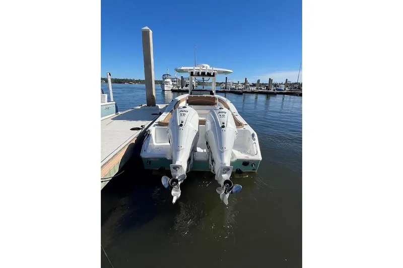 Slide: The Image of 2023 Sea Hunt Ultra 305 SE boat docked at marina, featuring dual engines. - 7