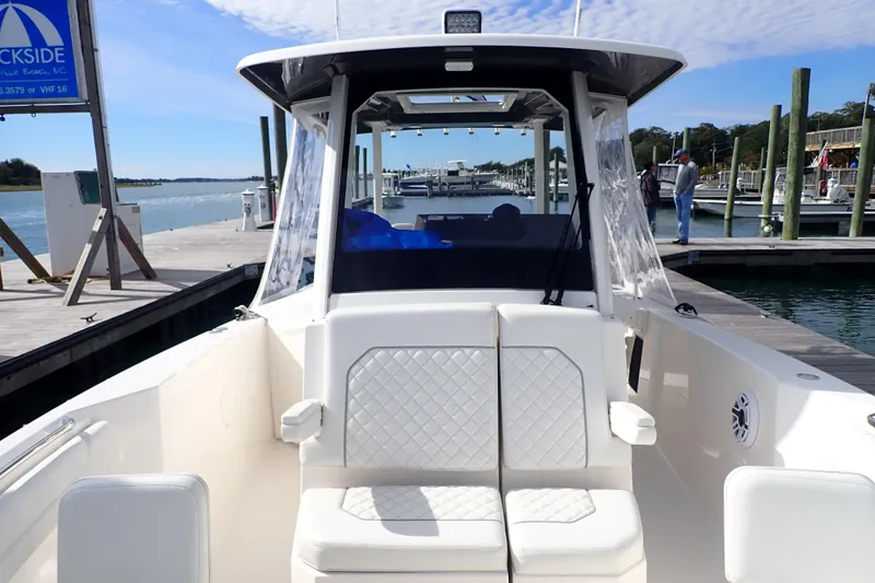Slide: The Image of 2024 Pursuit S 288 Sport boat docked at marina, featuring comfortable seating. - 26