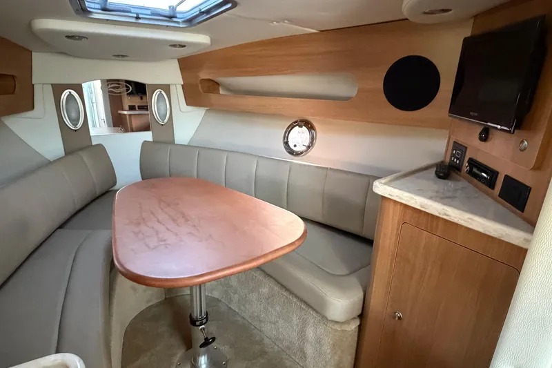 Slide: The Image of 2015 Rinker 290 Express Cruiser interior with dining area and TV. - 10