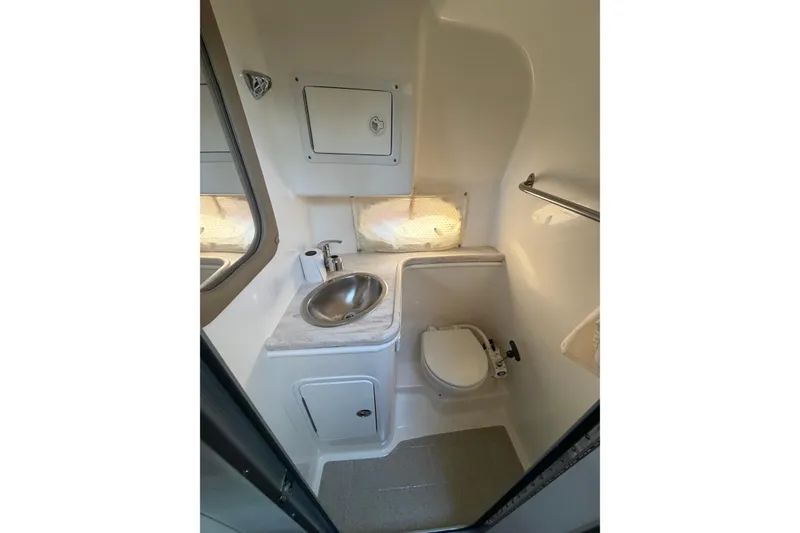 Slide: The Image of 2015 Rinker 290 Express Cruiser bathroom with sink, toilet, and storage cabinet. - 11