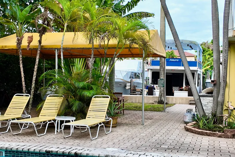 Slide: The Image of Poolside view with lounge chairs, tropical plants, and a 1996 Catamaran Cruisers Aqua Cruiser 44. - 28