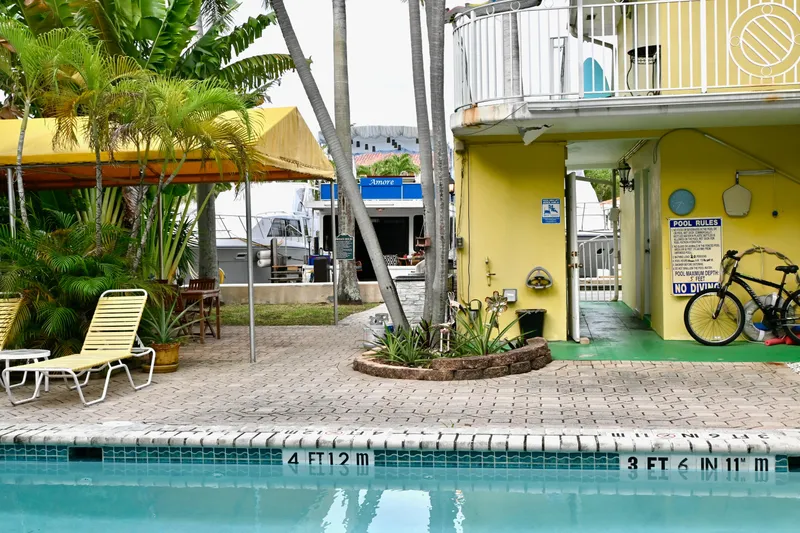Slide: The Image of Poolside view with yellow building, lounge chairs, and a Catamaran Cruisers Aqua Cruiser 44 in the background. - 29