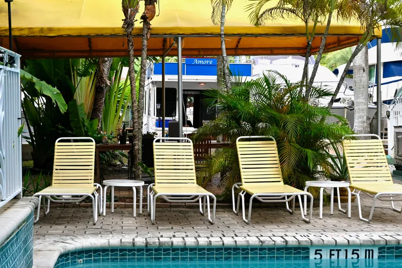 Slide: The Image of Poolside view with yellow lounge chairs, tropical plants, and a 1996 Catamaran Cruisers Aqua Cruiser 44. - 30
