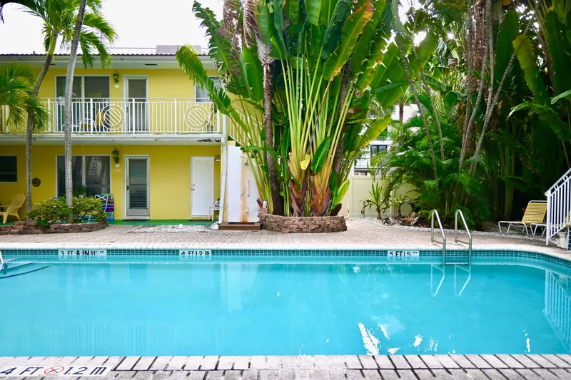 Slide: The Image of Tropical poolside with yellow building, lush greenery, and inviting lounge chairs. - 31