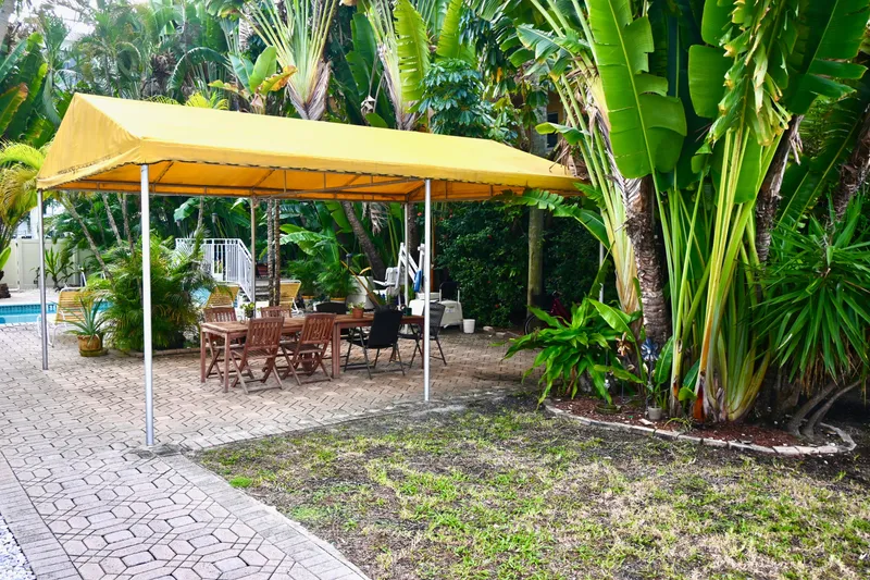Slide: The Image of Outdoor patio with yellow canopy, wooden furniture, surrounded by lush tropical plants. - 34