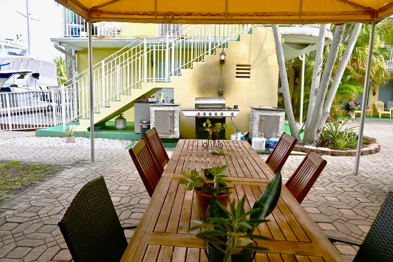 Slide: The Image of Outdoor patio with wooden dining table, plants, and a barbecue grill under a yellow canopy. - 37