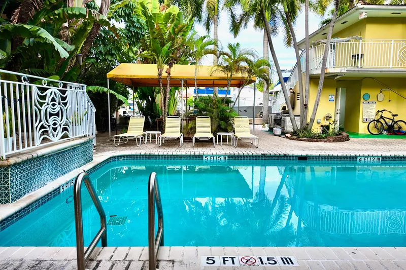 Slide: The Image of Tropical poolside with lounge chairs, palm trees, and a yellow building in a serene setting. - 38
