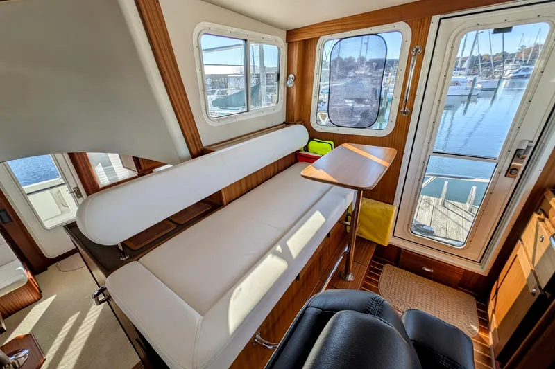 Slide: The Image of Interior of 2015 American Tug 435 with seating, table, and marina view through windows. - 53