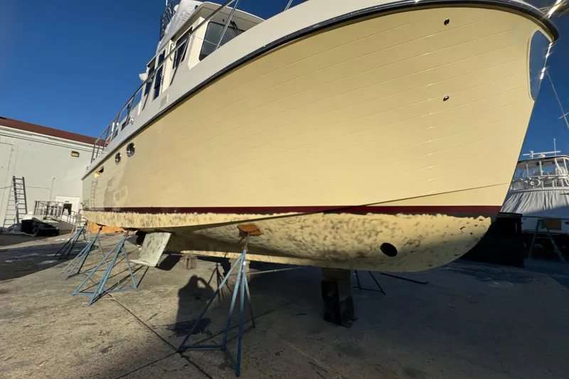 Slide: The Image of 2015 American Tug 435 boat on stands in a shipyard under clear blue sky. - 87