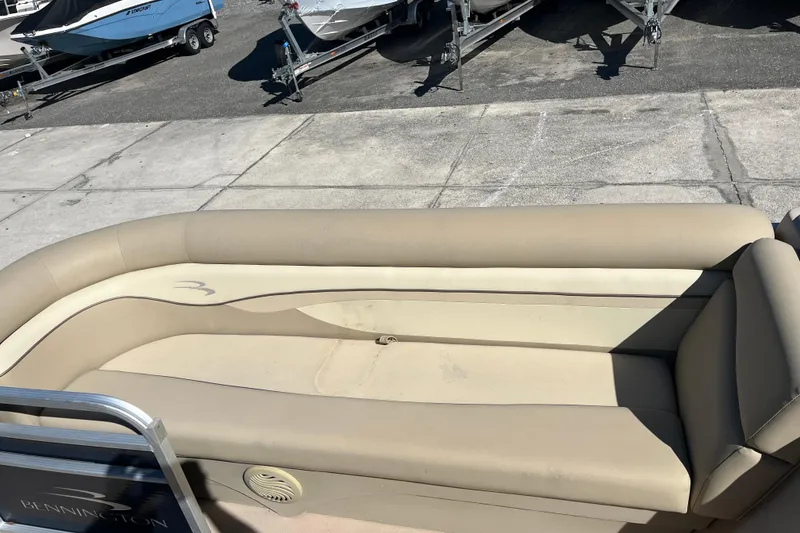 Slide: The Image of 2014 Bennington 22SSX boat with beige seating, parked on a concrete surface. - 10