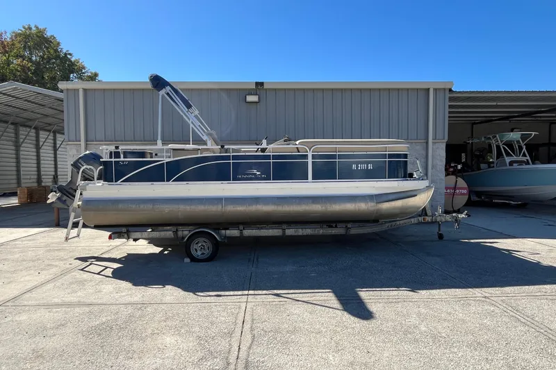 Slide: The Image of 2014 Bennington 22SSX pontoon boat on trailer, parked outside a metal building. - 19