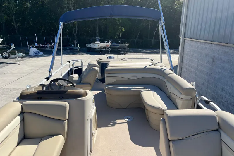 Slide: The Image of 2014 Bennington 22SSX pontoon boat with beige seating and blue canopy in a sunny marina. - 6