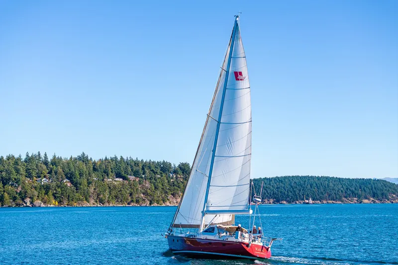 Slide: The Image of Sailing yacht Ron Holland 50, 2013 model, cruising on blue waters near a forested shoreline. - 6