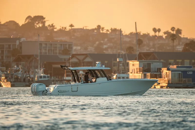 The Image of 2025 Robalo R360 Center Console boat cruising at sunset near marina. - 0