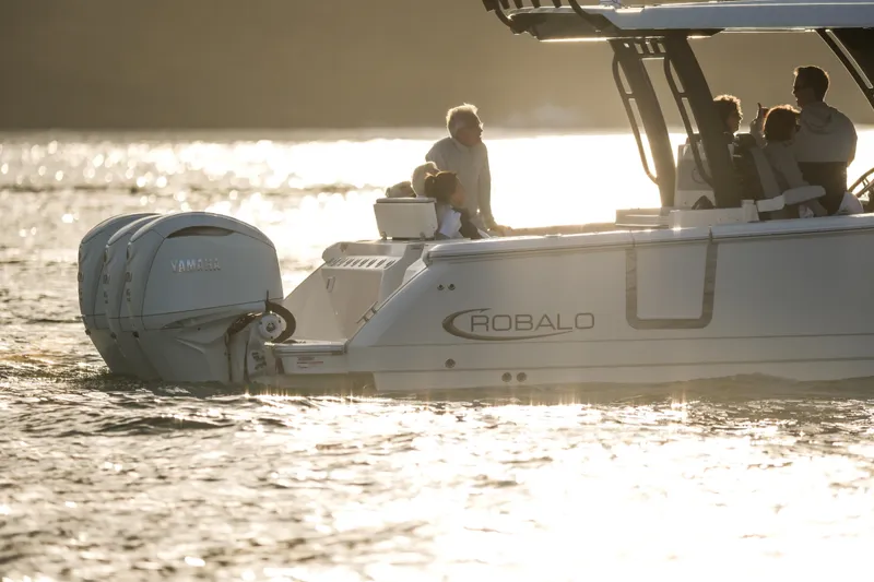 Slide: The Image of 2025 Robalo R360 Center Console boat on water at sunset with passengers. - 15
