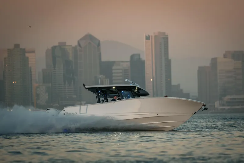 Slide: The Image of 2025 Robalo R360 Center Console boat cruising near city skyline at sunset. - 16