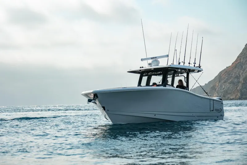 Slide: The Image of 2025 Robalo R360 Center Console boat on open water near rocky coastline. - 18