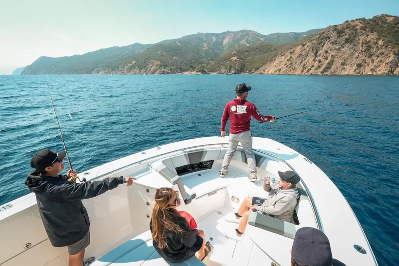 Slide: The Image of People fishing on a 2025 Robalo R360 Center Console boat near scenic coastline. - 21