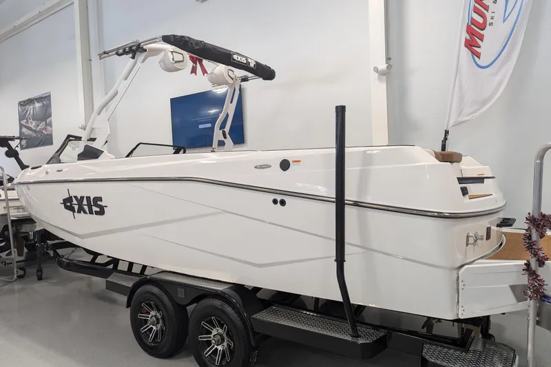 Slide: The Image of 2026 Axis T250 boat on trailer in showroom, white exterior, sleek design. - 2