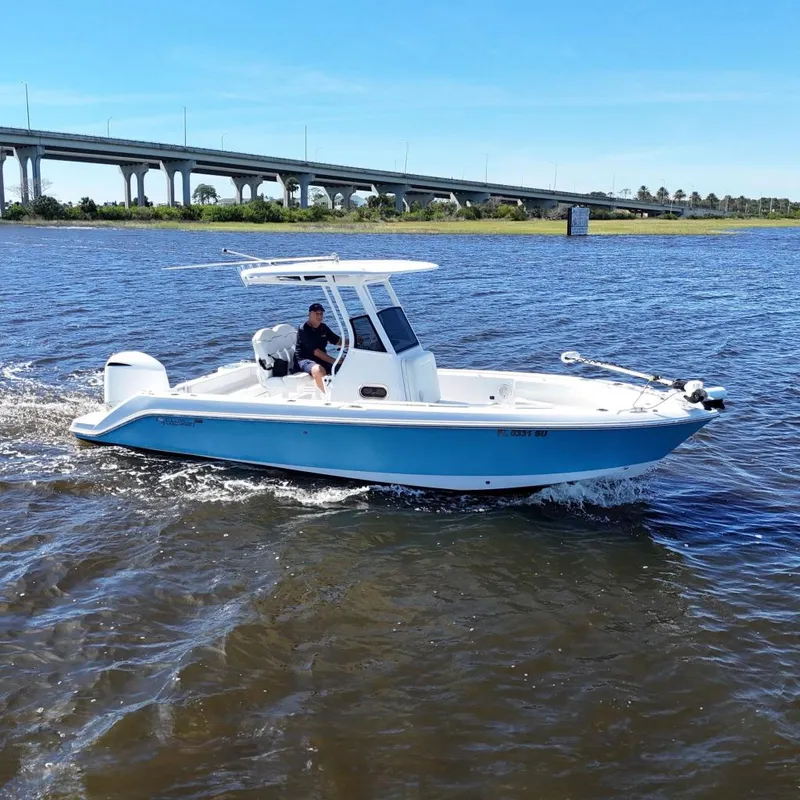 The Image of 2019 Edgewater 230CC boat cruising on a scenic lake under a clear blue sky. - 0