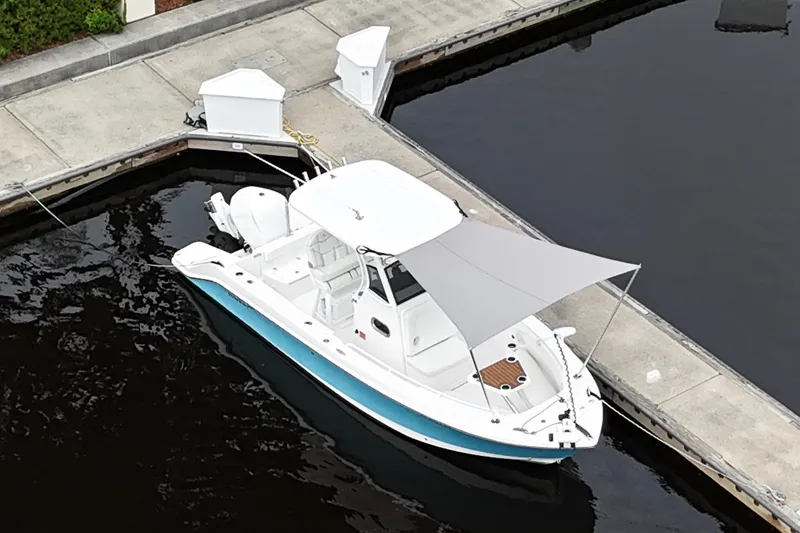 Slide: The Image of 2019 Edgewater 230CC boat with open hatch and ladder, docked on calm water. - 23