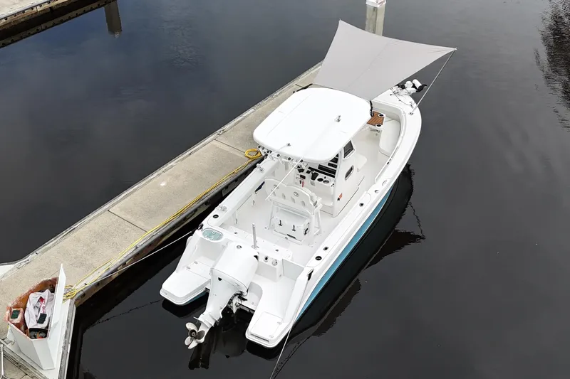 Slide: The Image of 2019 Edgewater 230CC boat with outboard motor, docked on calm water. - 25