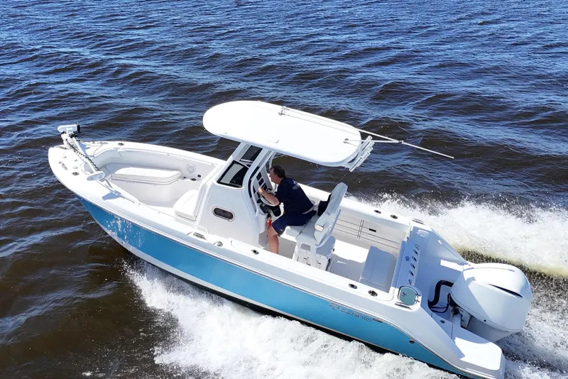 Slide: The Image of 2019 Edgewater 230CC boat cruising on a calm lake with a person at the helm. - 9
