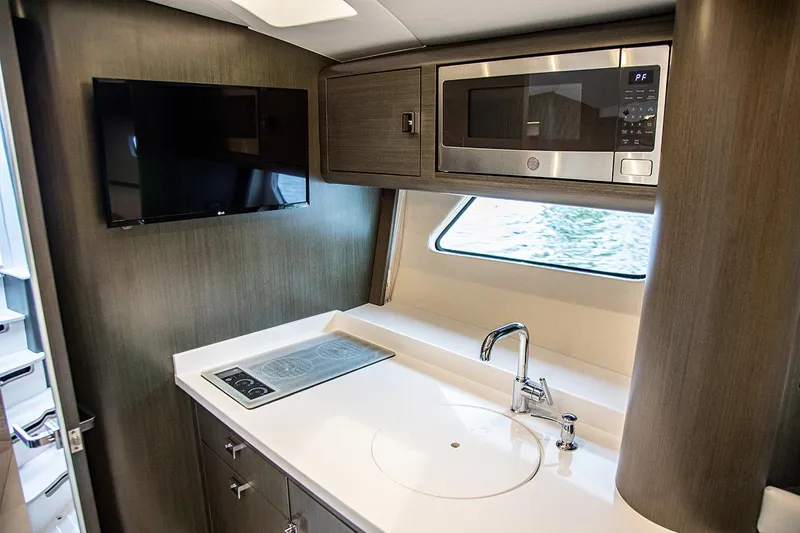 Slide: The Image of Manufacturer Provided Image: Modern kitchen area in 2021 Intrepid 410 Evolution yacht with microwave, TV, and stovetop. - 14