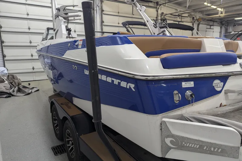 Slide: The Image of 2021 Malibu Wakesetter 22 LSV boat in garage, blue and white exterior, on trailer. - 17