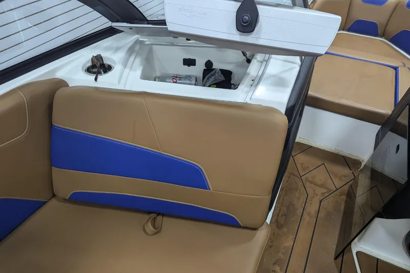 Slide: The Image of 2021 Malibu Wakesetter 22 LSV interior with tan and blue seating, open storage compartment. - 23