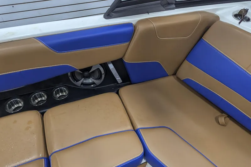 Slide: The Image of 2021 Malibu Wakesetter 22 LSV interior with tan and blue seating, cup holders, and speaker. - 24