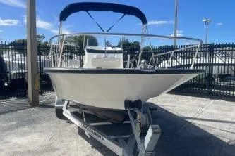 Slide: The Image of 2024 Boston Whaler 190 Montauk boat on trailer, under blue sky, in fenced area. - 4