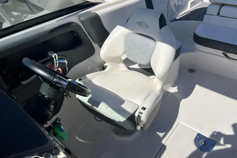 Slide: The Image of 2023 Chaparral 270 OSX boat cockpit with white captain's chair and steering wheel. - 21