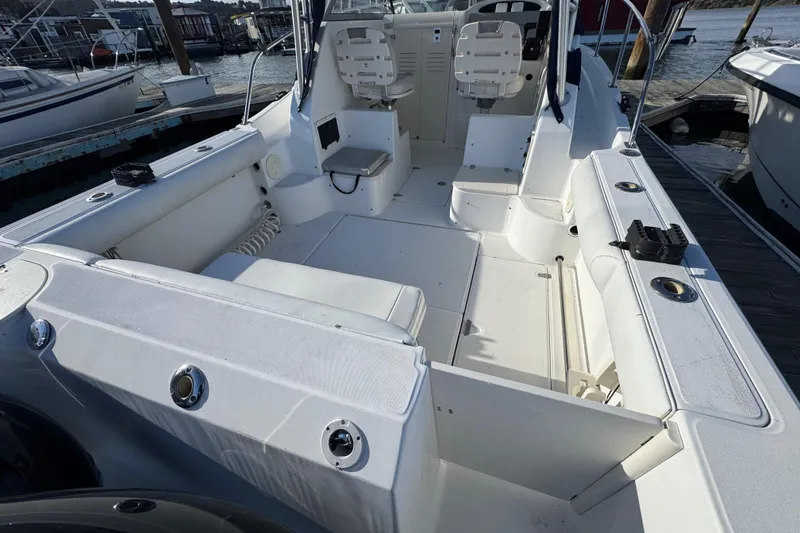 Slide: The Image of 2004 Boston Whaler 255 Conquest boat interior, featuring seating and control area at dock. - 11
