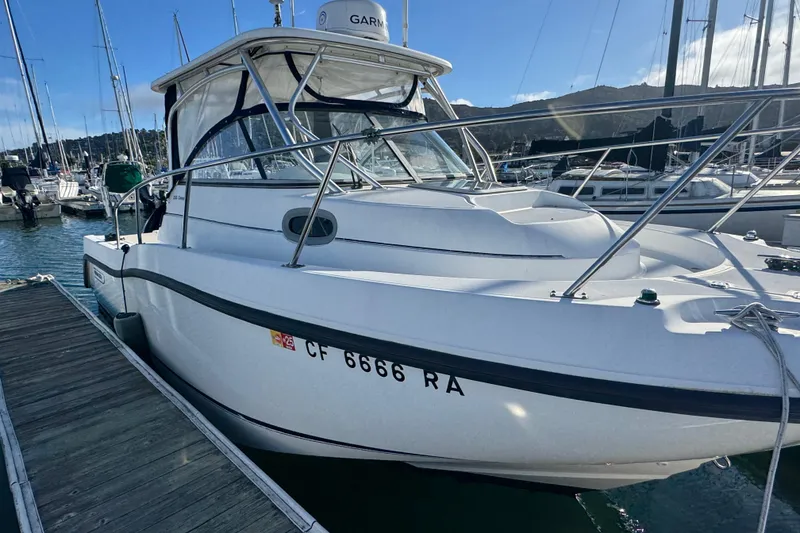 Slide: The Image of 2004 Boston Whaler 255 Conquest boat docked at a marina under clear skies. - 7