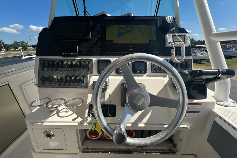 Slide: The Image of Control panel of a 2009 Scarab Sport 30 boat with steering wheel and navigation equipment. - 28