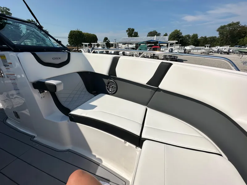 Slide: The Image of 2023 Chaparral 270 OSX boat interior with white and black seating, docked outdoors. - 12