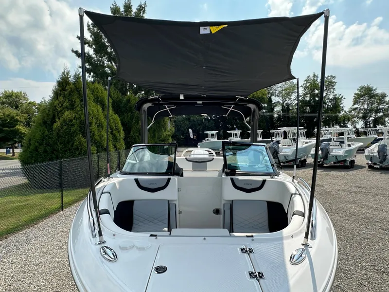 Slide: The Image of 2023 Chaparral 270 OSX boat with canopy, parked outdoors on gravel. - 20