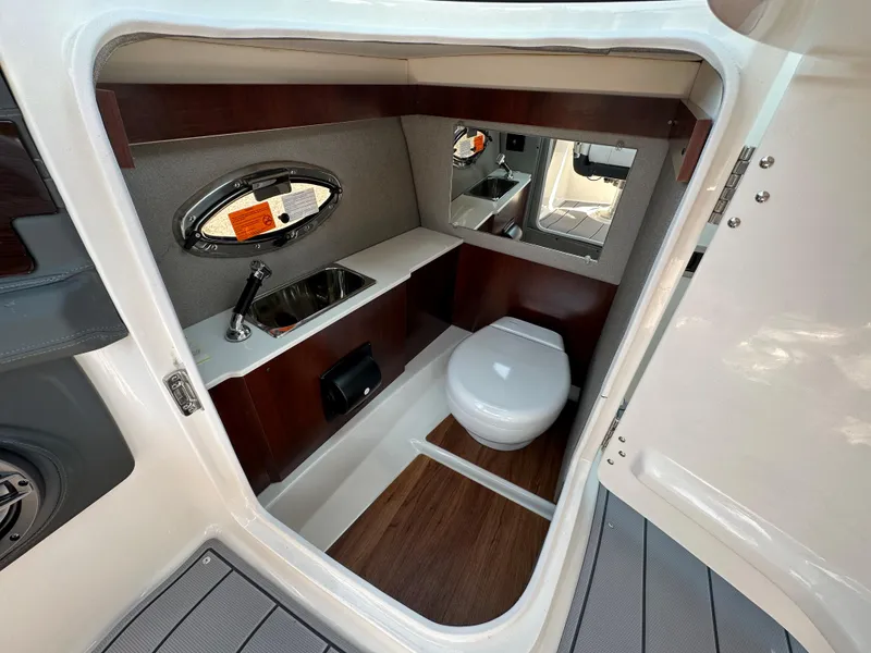 Slide: The Image of 2023 Chaparral 270 OSX boat interior with sink, toilet, and wood accents. - 34
