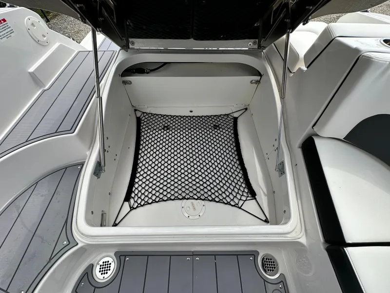 Slide: The Image of 2023 Chaparral 270 OSX boat storage compartment with netting and seating area. - 48