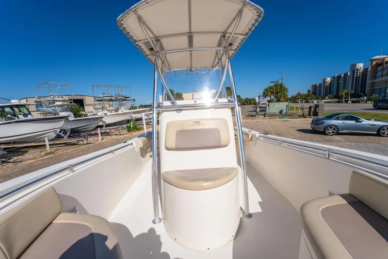Slide: The Image of 2017 Cobia 220 Center Console boat with T-top, parked near other boats and a car. - 25