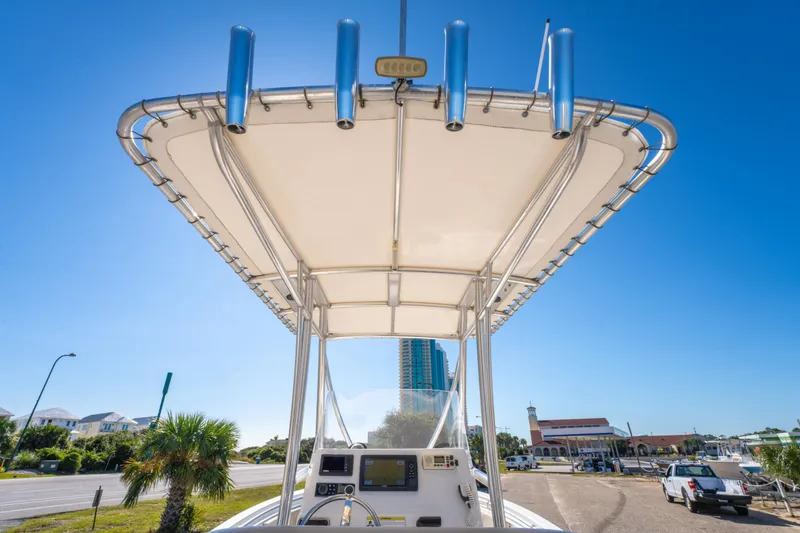 Slide: The Image of 2017 Cobia 220 Center Console boat with T-top, parked near a road under clear blue sky. - 27