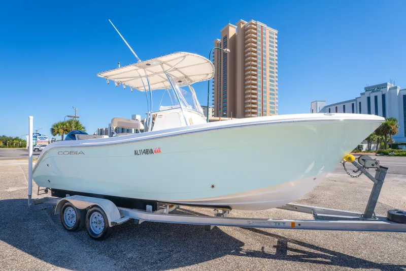 Slide: The Image of 2017 Cobia 220 Center Console boat on trailer, urban background, clear blue sky. - 4