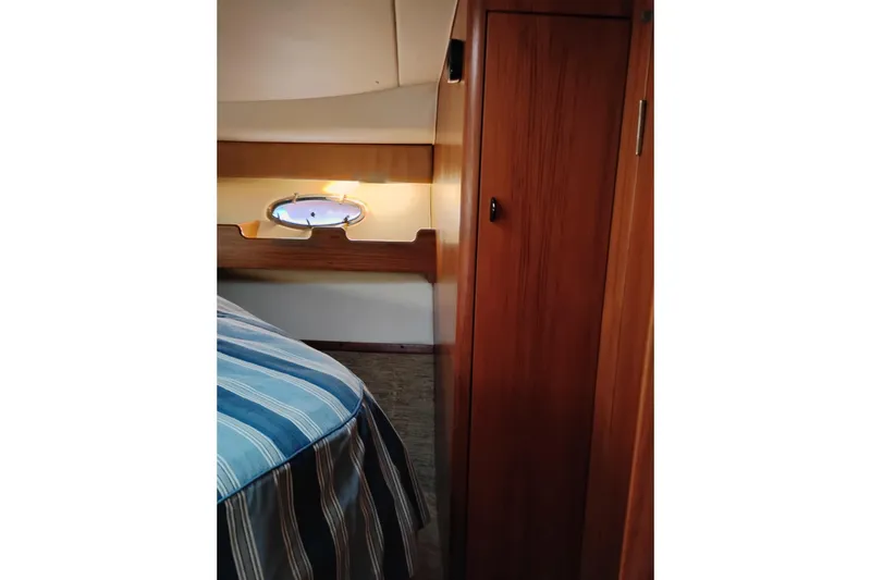 Slide: The Image of Interior of 1997 Tiara 3700 Open yacht with wood paneling and striped bedding. - 47