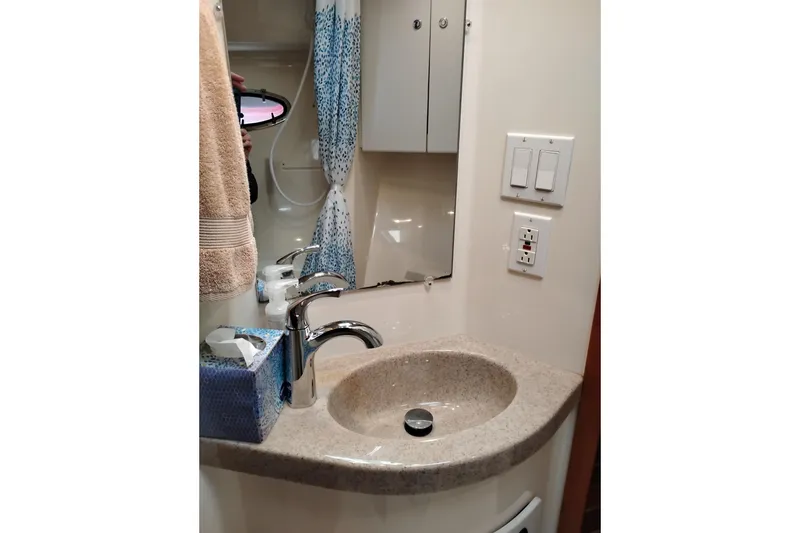Slide: The Image of Bathroom sink area in a 1997 Tiara 3700 Open yacht, featuring a mirror and faucet. - 50