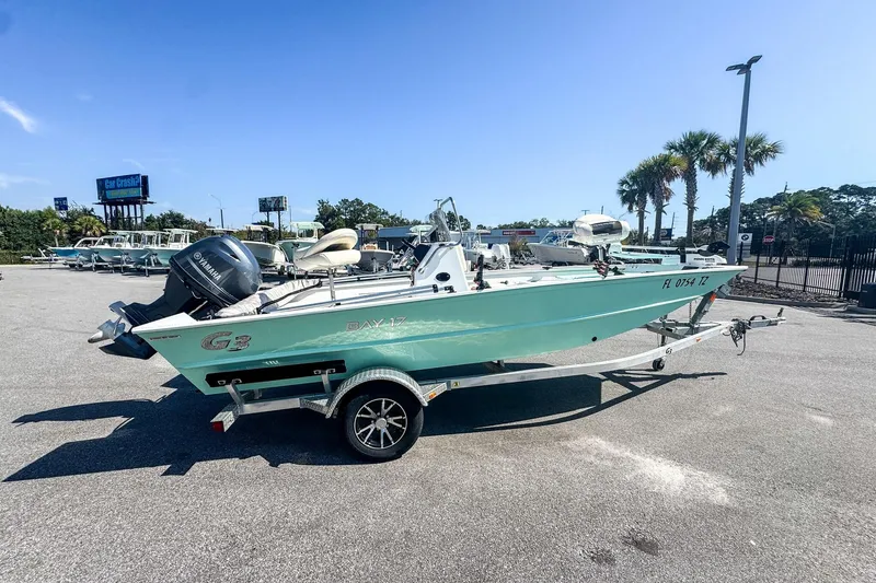 Slide: The Image of 2023 G3 Bay 17 boat on trailer, parked outdoors under clear blue sky. - 2